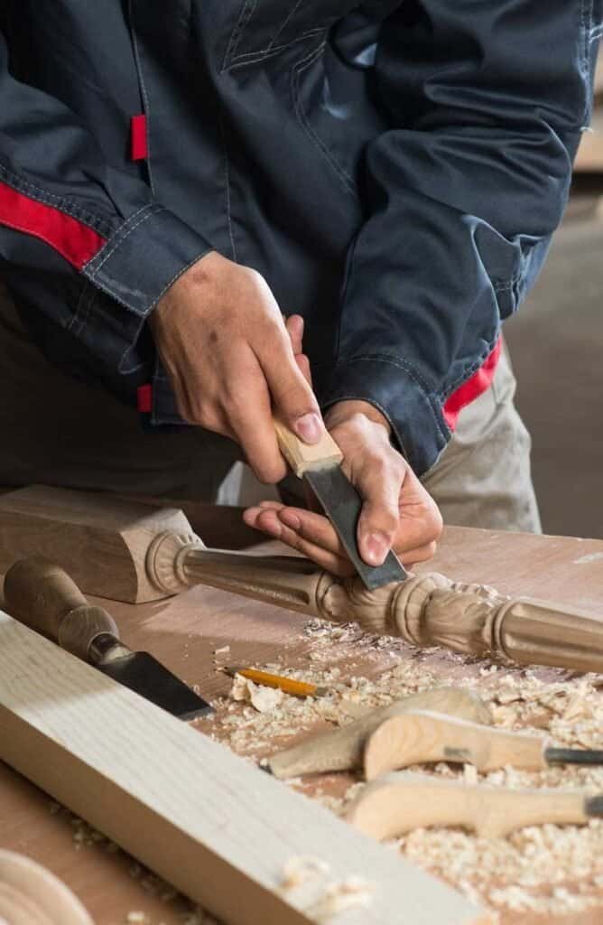Carpenter shaping wood with hand tools in workshop.