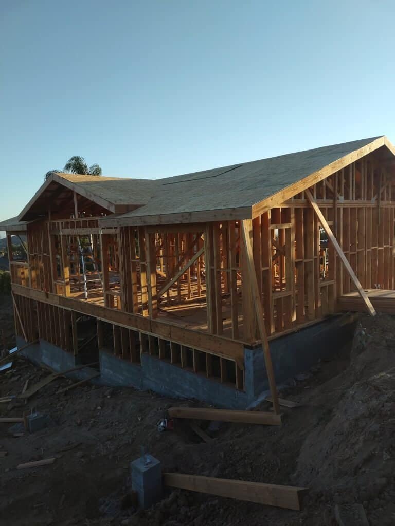 Wood framing of a house under construction with a clear sky background.