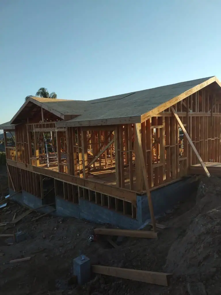 Wood framing of a house under construction with a clear sky background.