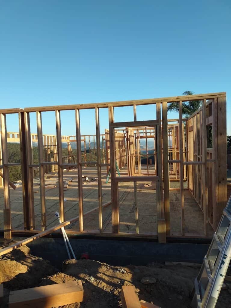 Wooden house framing under construction with clear blue sky.