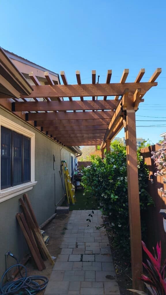 Wooden pergola being built on house patio for outdoor shade.