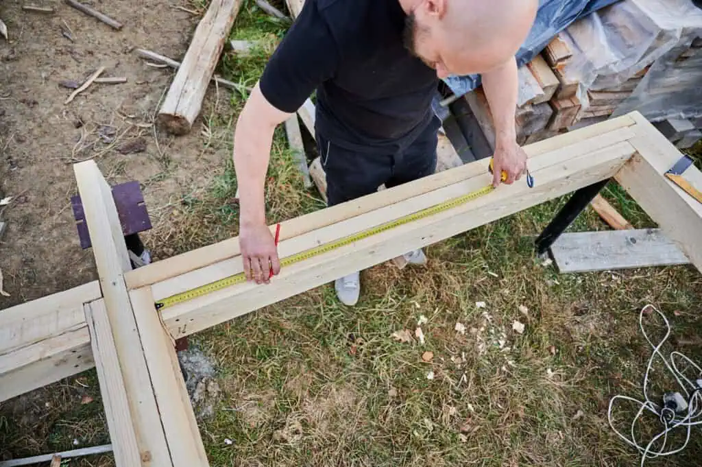 Carpenter measuring wood for framing at a construction site.