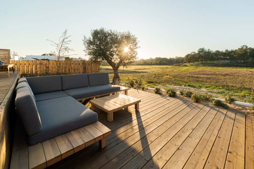 Outdoor wooden deck with seating and scenic rural landscape at sunset.