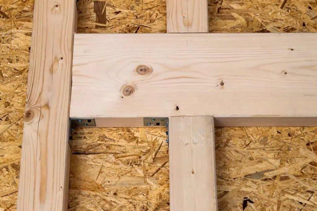 Close-up of wooden framing with metal connector at construction site.