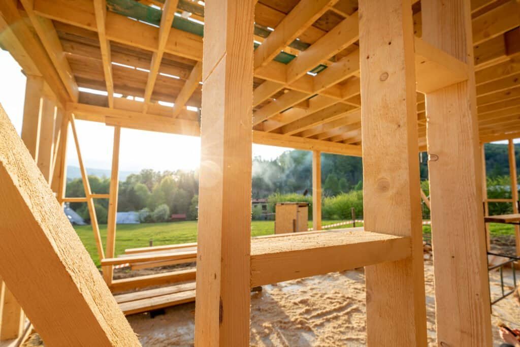 Wooden framing structure under construction with sunlight in the background.